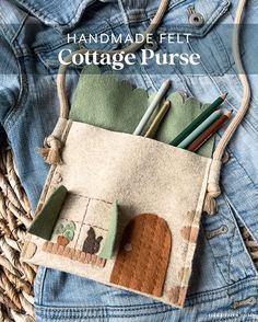 the handmade felt cottage purse is sitting on top of a basket with pens and pencils in it