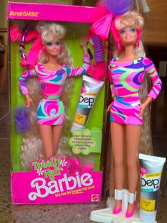 two barbie dolls standing next to each other in front of a box with toothpaste on it