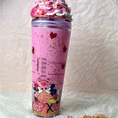 a pink tumbler cup with minnie mouses on it next to some confetti