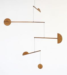 three wind chimes hanging in the air with wooden discs attached to them and one has a light bulb on each side