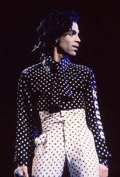 a woman with black and white polka dots on her shirt is standing in front of a ruler