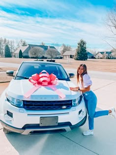 a woman standing next to a white car with a pink bow on it