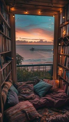 an open window with bookshelves and lights in the room, overlooking the ocean