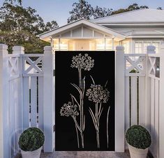 a white fence with two potted plants next to it and a black screen on the door