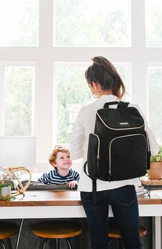 Rich black weather resistant nylon with a pop of peacock blue on the interior. Black leather detail and gold hardware make this a stunning backpack! This lightweight and beautifully designed backpack with its versatile style and classic design can easily be used as a diaper bag, work bag, a travel bag, or for any other purpose. MATERIAL wipeable, weather resistant black nylon wipeable peacock blue nylon lining black full grain leather gold hardware DETAILS backpack with convenient top grab handl Chic Work Bag, Designer Work Bag, Stylish Work Bag, Designer Travel Bags, Best Work Bag, Black Outlet, Designer Diaper Bag, Laptop Bag For Women, Travel Bags For Women