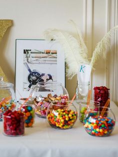 there are many candy in glass bowls on the table next to some pictures and decorations