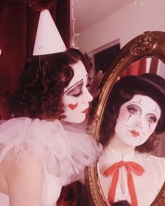 a woman is dressed up as a clown and looking at her reflection in the mirror