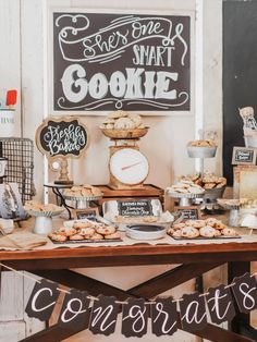 a table topped with lots of food next to a chalkboard sign that says she's one smart cookie