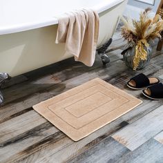 a pair of slippers sitting on the floor next to a bathtub and rug