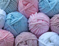 several balls of yarn in pastel blue, pink and white colors are piled together