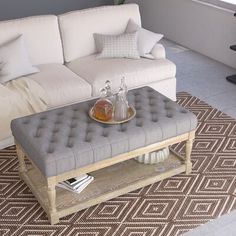 a living room with a couch, ottoman and coffee table in front of a window