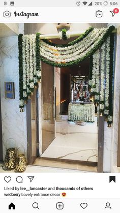 an entrance decorated with white flowers and greenery for a wedding or reception at the hotel