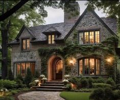 a stone house with lots of windows and steps leading up to the front door is lit by lights