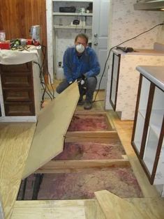 a man kneeling down on the floor in front of some wood planks that have been cut open