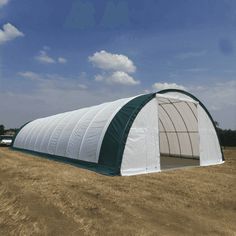 a large green and white structure in the middle of a field with cars parked nearby