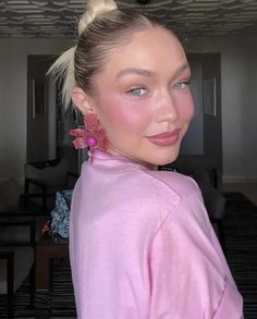 a woman with blonde hair and blue eyes is wearing pink clothing, posing for the camera