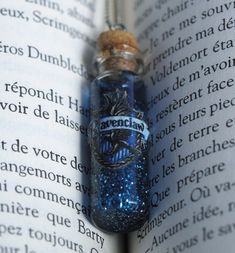 an open book with a glass bottle filled with blue liquid