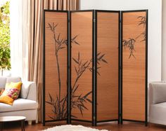 a room divider with bamboo leaves painted on the side and two white couches