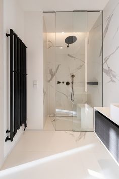 a white bathroom with black radiator and glass partitions on the shower wall