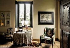 a living room with a table and chair next to a large window in the corner