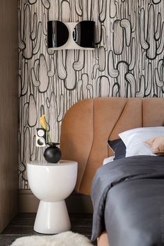 a modern bedroom with black and white wallpaper, an upholstered headboard