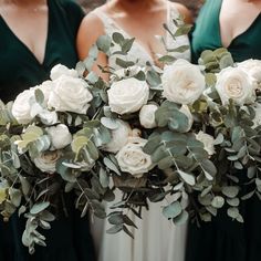 three bridesmaids in green dresses holding bouquets of white roses and eucalyptus leaves