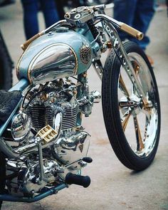 a silver motorcycle parked on top of a cement floor next to other motorcycles and people