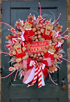 a wreath with gingerbread cookies and candy canes on the front door for christmas