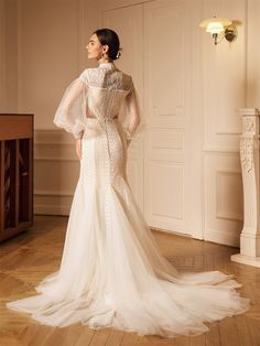 a woman in a wedding dress standing on a wooden floor with her back to the camera