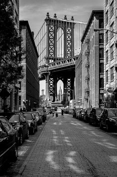 black and white photograph of cars parked in front of the manhattan bridge, new york city