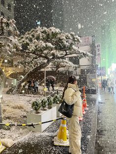 a woman is standing in the snow near a tree