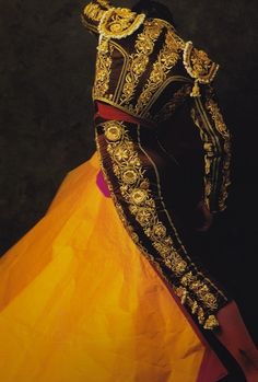 a woman in a yellow and black dress is wearing an elaborate headpiece with gold accents