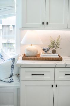 a kitchen with white cupboards and a basket on the counter next to a window