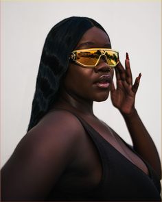 a woman wearing sunglasses and holding her hand up to her face