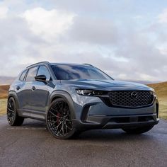 the front end of a gray mazda cx - 5 parked on a paved road