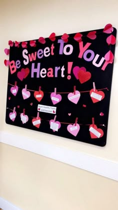 a sign that says be sweet to your heart hanging on a wall with hearts attached to it