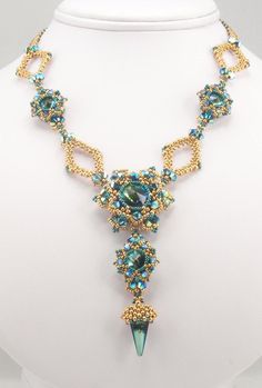 the necklace is adorned with blue beads and an arrow shaped beaded pendant on a white mannequin