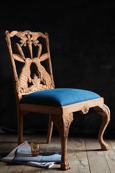 a wooden chair sitting on top of a hard wood floor next to a blue cushion