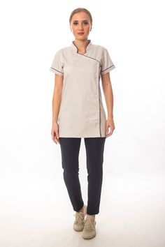 Step up your spa or hotel uniform game with this short-sleeve, mock-neck women's tunic featuring handy side snaps. Perfect for a variety of professional settings, including spa attendant and hotel staff uniforms. You could personalize your spa tunic with embroidery. The black bias tape detail adds a touch of sophistication and elegance to the design, making it suitable for various professional settings. It is perfect for spa attendants, hotel staff, and other professionals who want to look and feel their best while on the job. Spa Uniform Ideas Style, Housemaid Uniform, Hotel Uniform Design, Spa Uniform, Beauty Tunics, Hotel Uniform, Staff Uniforms, Hotel Staff, Uniform Design