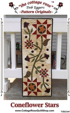 a quilted wall hanging on the side of a white bench with flowers and leaves