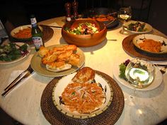 a table topped with lots of plates and bowls filled with different types of food on top of it