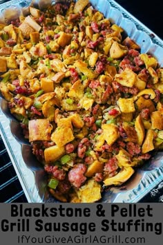 a casserole dish with meat and vegetables in it on a baking sheet that says blackstone & pellet grill sausage stuffing