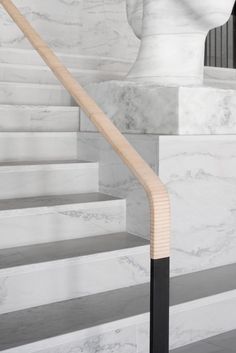 a white marble staircase with wooden handrails and black metal railing in front of it