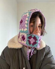 a woman wearing a crocheted hat with a scarf around her neck and hood