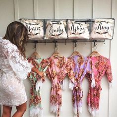 a woman is looking at some robes hanging on a rack in front of the wall