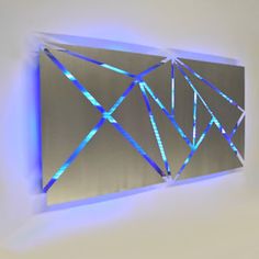 a metal wall sculpture with blue lights on it's sides and an abstract design in the middle