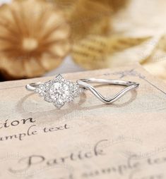 a diamond ring sitting on top of an old book next to some other items in the background