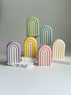 five candles are stacked on top of each other in pastel colors and one candle is lit