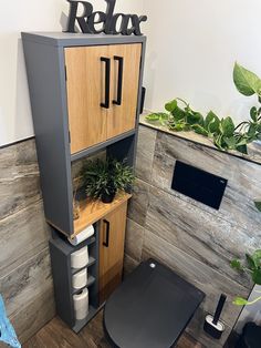 an office cubicle with plants in the corner and a sign above it that says relax