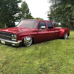 a red truck parked on top of a lush green field